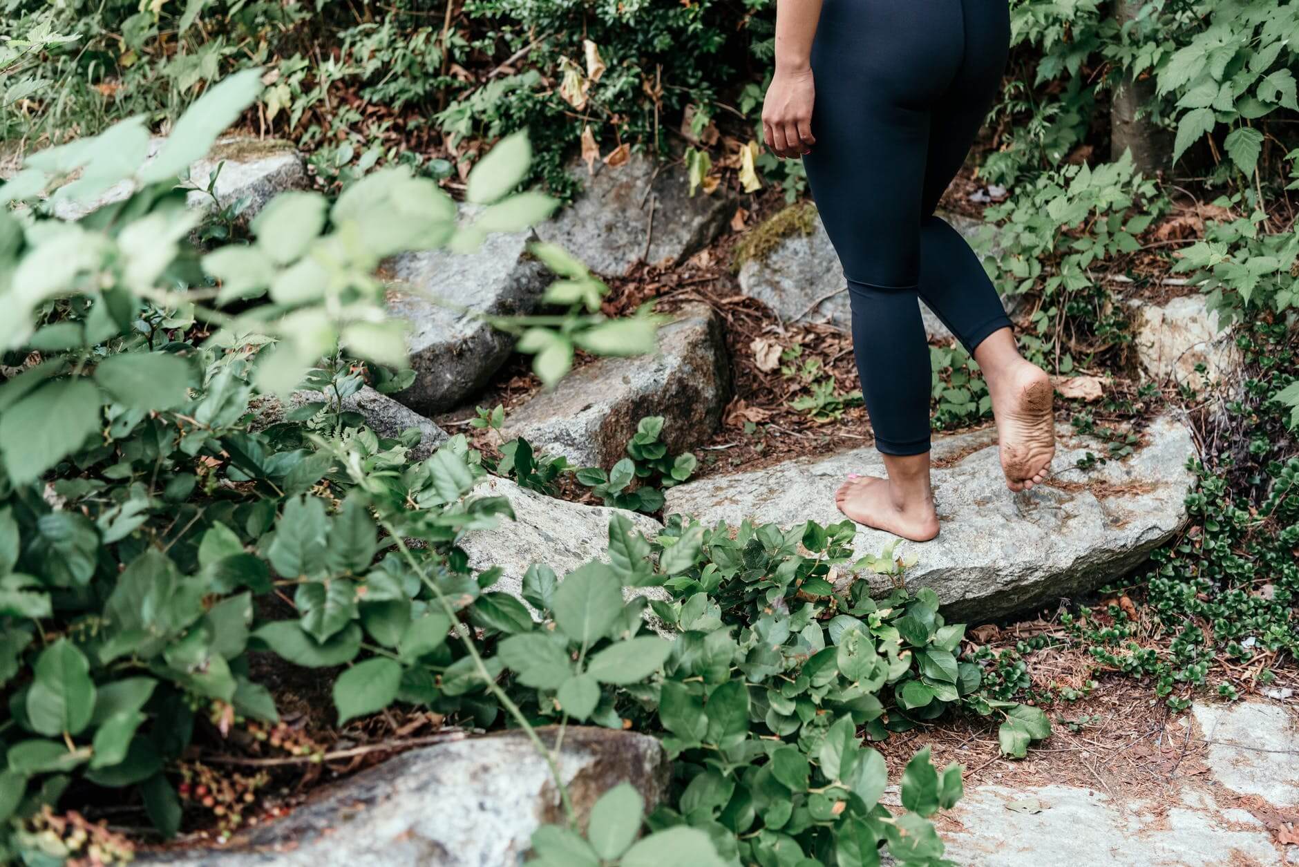 person in black leggings walking on rock